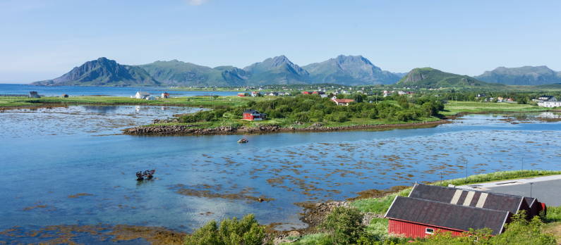 Kystlandskap i B&oslash; i Vester&aring;len med hus, sj&oslash; og fjell i bakgrunnen