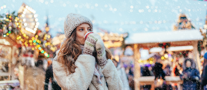 Girl walking in Christmas markets drinking hot chocolate