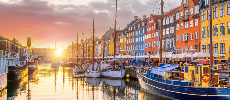 De fargerike bygningene og b&aring;tene i Nyhavn i K&oslash;benhavn sett fra vannet i solnedgang