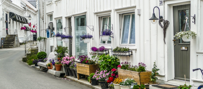 Hyggelig bygate i Flekkefjord med hvitmalte hus og blomster