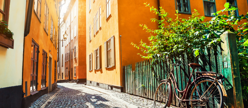 Solen skinner p&aring; en sykkel lent mot et gjerde i en smal gate i Stockholms eldste distrikt