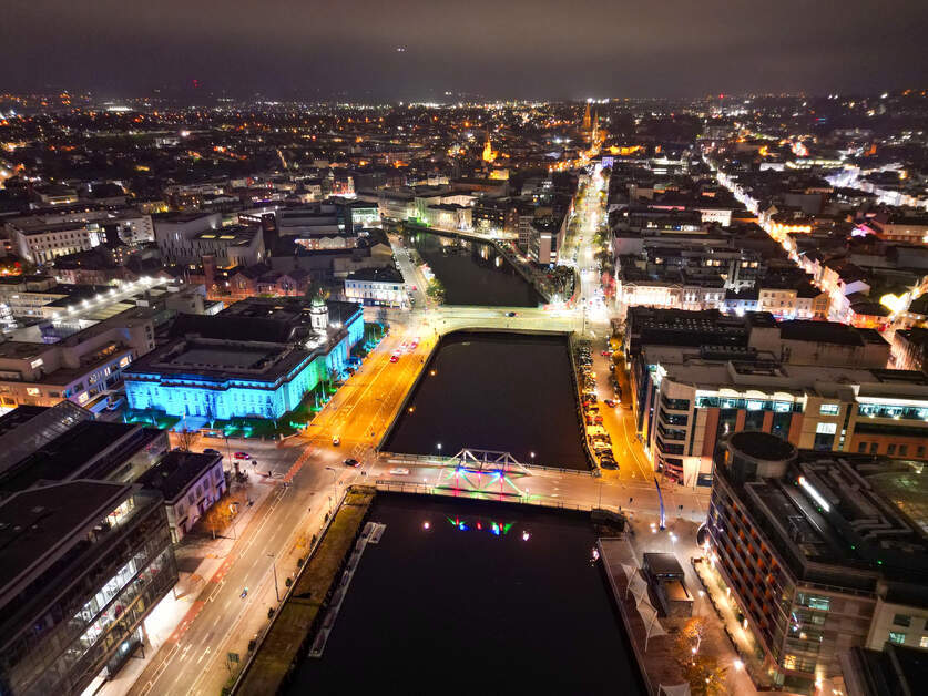 Aerial image of a river running through cork city with the roads  light up by street lights at night