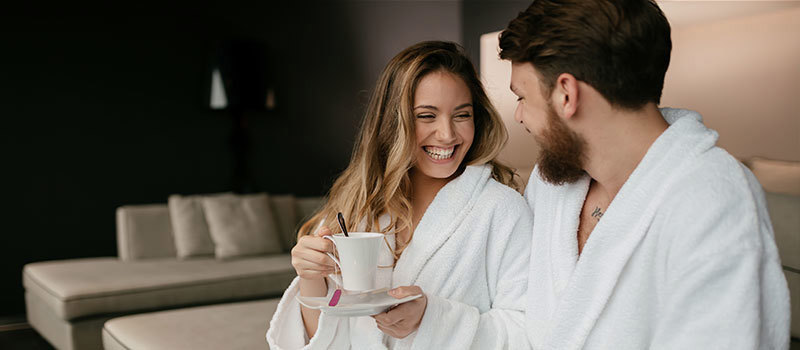 Couple drinking tea in hotel robes in hotel room