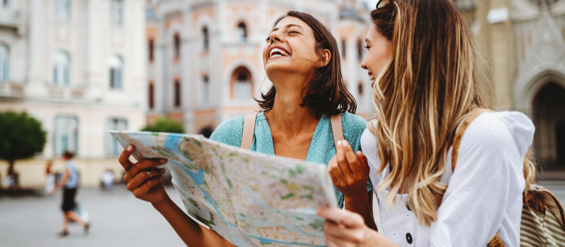 Two girls laughing, holding a map